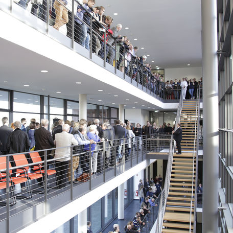 Das Auditorium steht am Geländer und lauscht den Grußworten des Rektors der Universität Rostock Prof. Dr. Wolfgang Schareck. © 2015 Betrieb für Bau und Liegenschaften Mecklenburg-Vorpommern