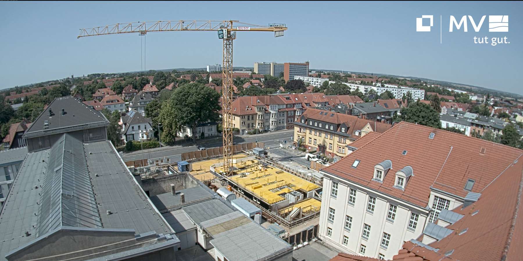 Blick auf eine Baustelle. Ein Kran steht in der Bildmitte. Im Hintergrund sind Häuser und der Horizont zu sehen. © 2022 SBL Schwerin
