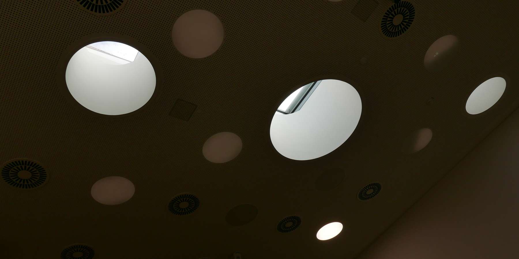 Die Belichtung des Hörsaals erfolgt durch Kreisrunde Öffnungen von oben © J.Rott