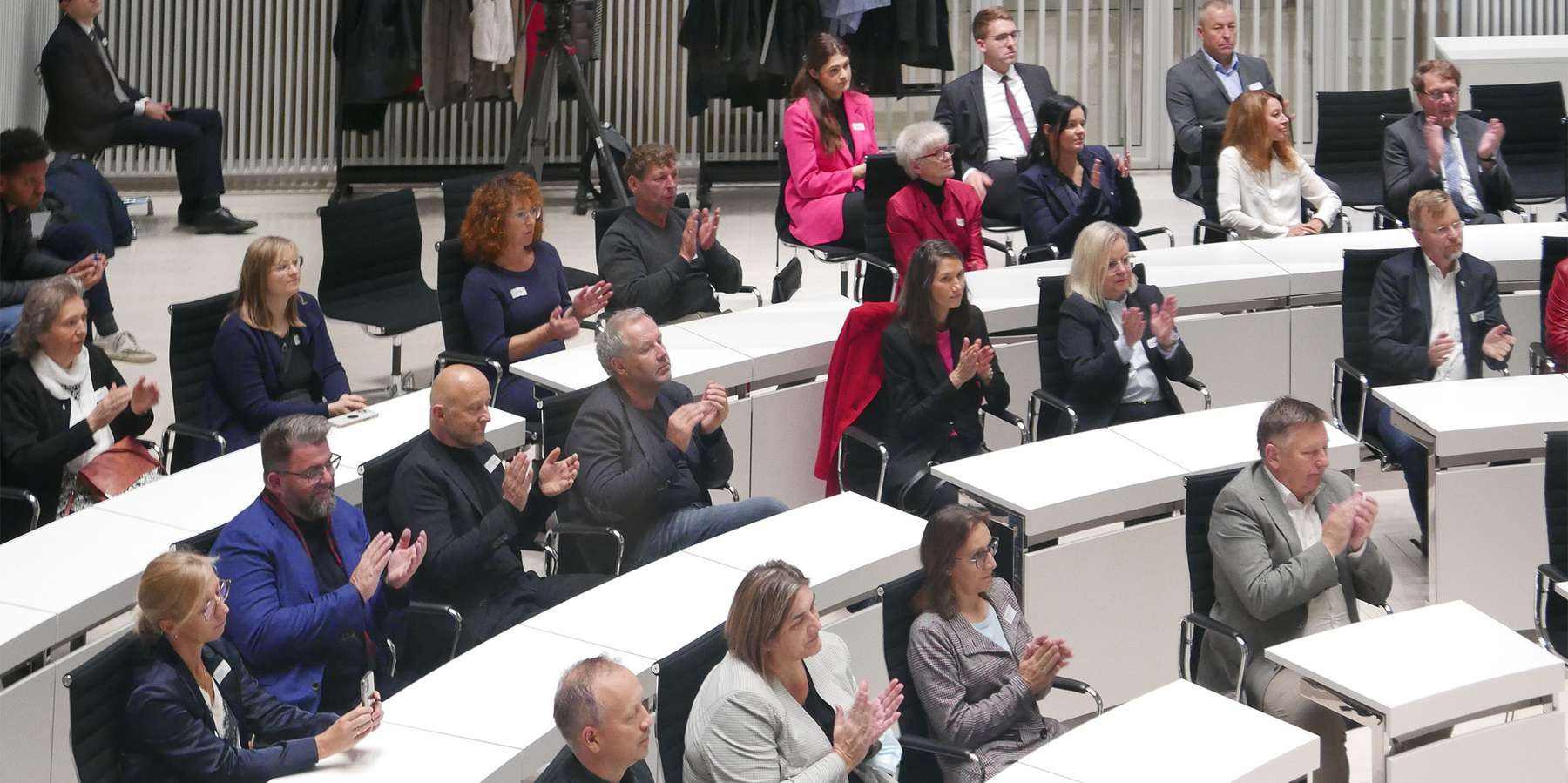 Menschen sitzen im Plenarsaal und applaudieren. © 2022 SBL Rostock