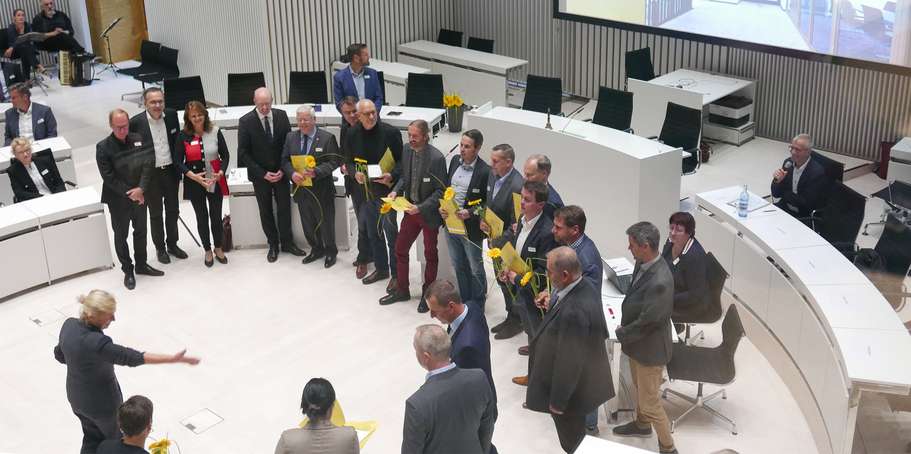 Menschen mit Blumen stehen im Plenarsaal. © 2022 SBL Rostock