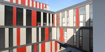 vertikale Fassadengliederung im Innenhof mit raumhohen Fenster-Elementen und ebenfalls raumhohen grauen und roten Fassadenplatten © 2007 Betrieb für Bau und Liegenschaften MV