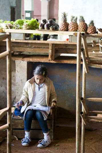 Ein Mädchen macht ihre Hausaufgaben am Marktstand ihrer Eltern in Havanna, Kuba 2012 Ein Mädchen macht ihre Hausaufgaben am Marktstand ihrer Eltern in Havanna, Kuba 2012
