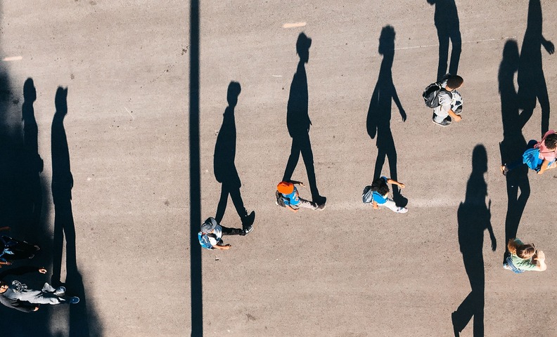 Junge Menschen aus der Vogelperspektive, die auf einem breiten Weg spazieren.