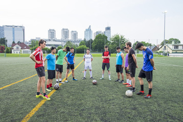 Der Fußballtrainer Daniel Kemper mit den Spielern auf einem Outdoor-Fußballplatz.