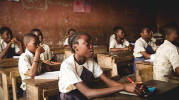 Afrikanische Kinder sitzen in einem Klassenraum.