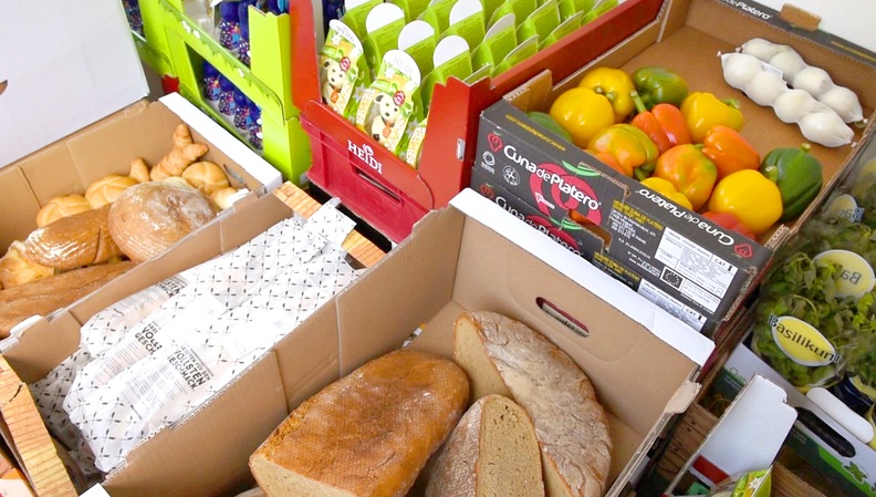 Übereinander gestapelte Kartonkisten mit Lebensmitteln wie Brot und Gemüse gefüllt.