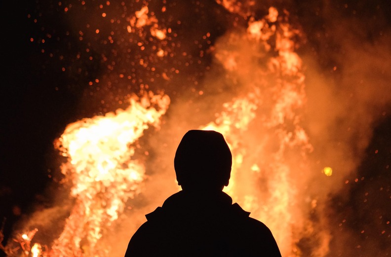 Dunkle Silhouette vor einem großen Feuer.