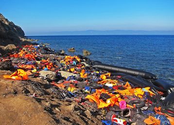 Schwimmwesten und ein Boot liegen am Strand