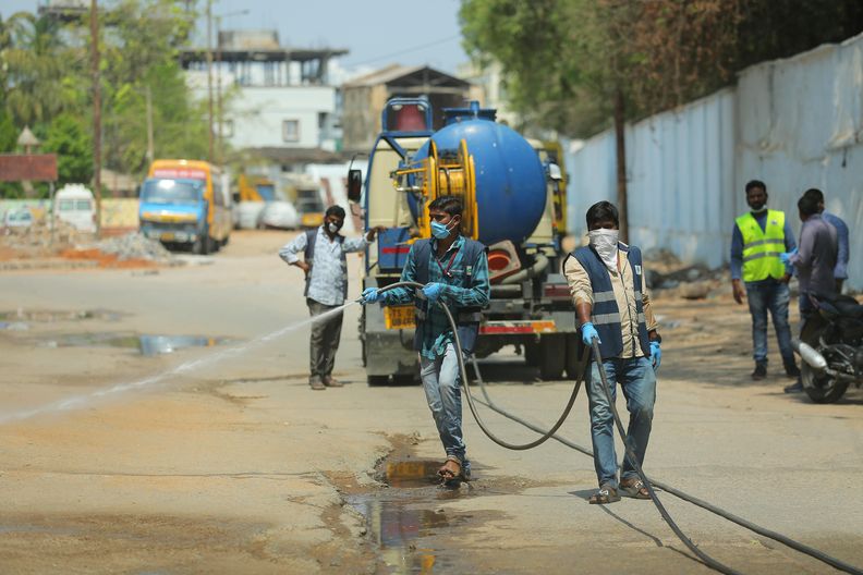 Menschen desinfizieren in Indien eine Straße