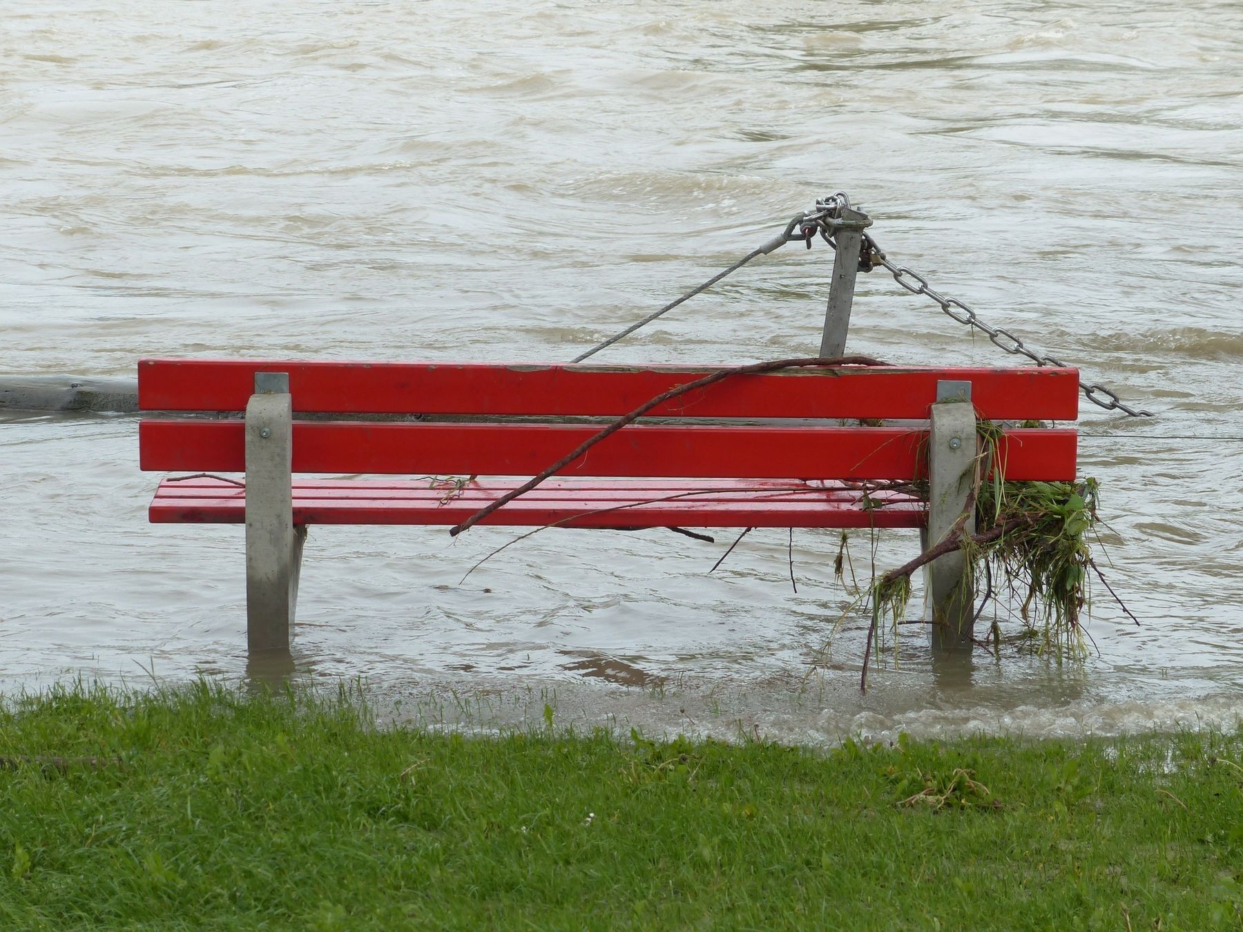 rote Parkbank steht im Hochwasser