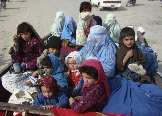 Kinder sitzen dicht gedrängt in einem Transportwagen.