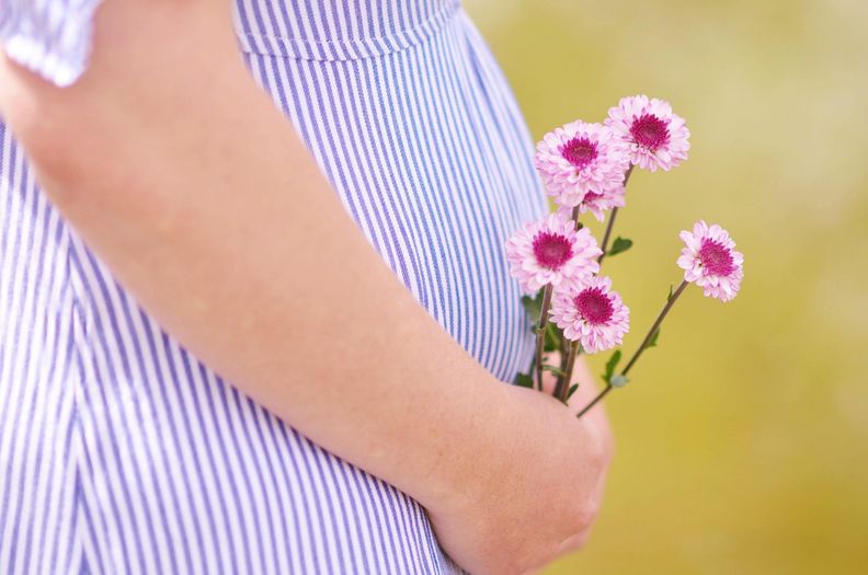 Schwangere Person hält Blumen