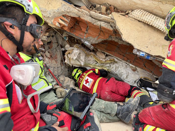 Rotes Kreuz Mitarbeiter suchen unter Trümmern nach Überlebenden